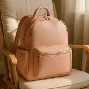 a pinkish diaper leather backpack sits on a chair